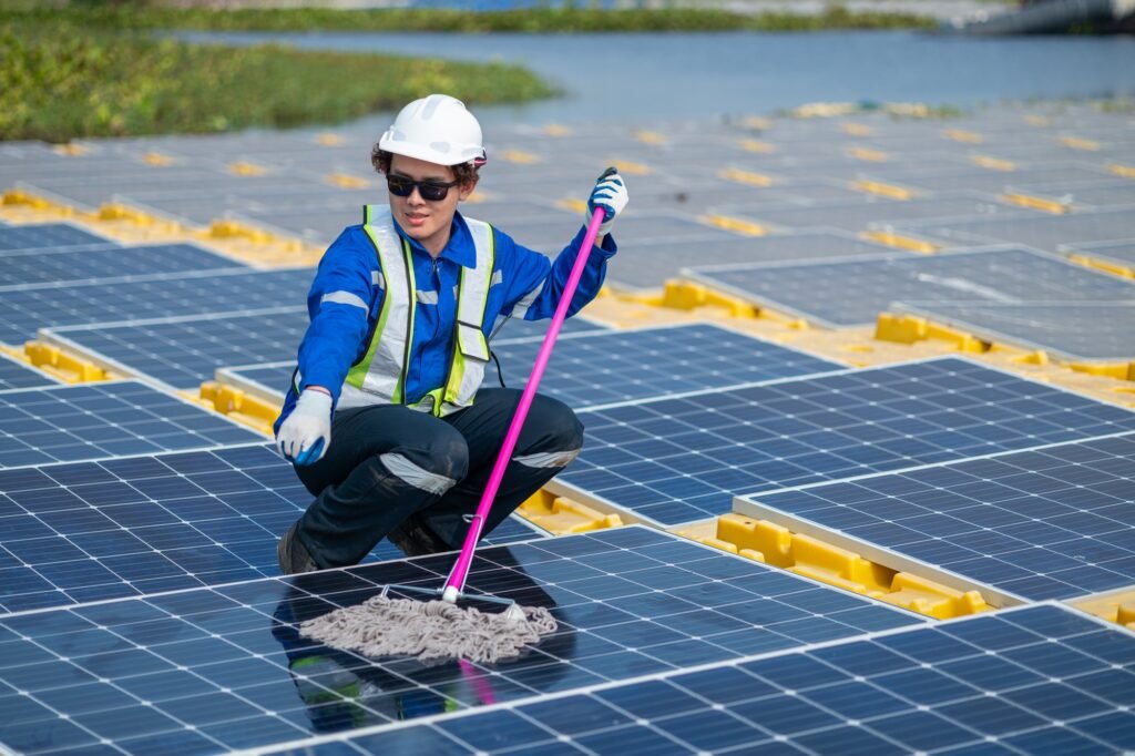 Worker Cleaning Solar Panels at Renewable Energy Farm